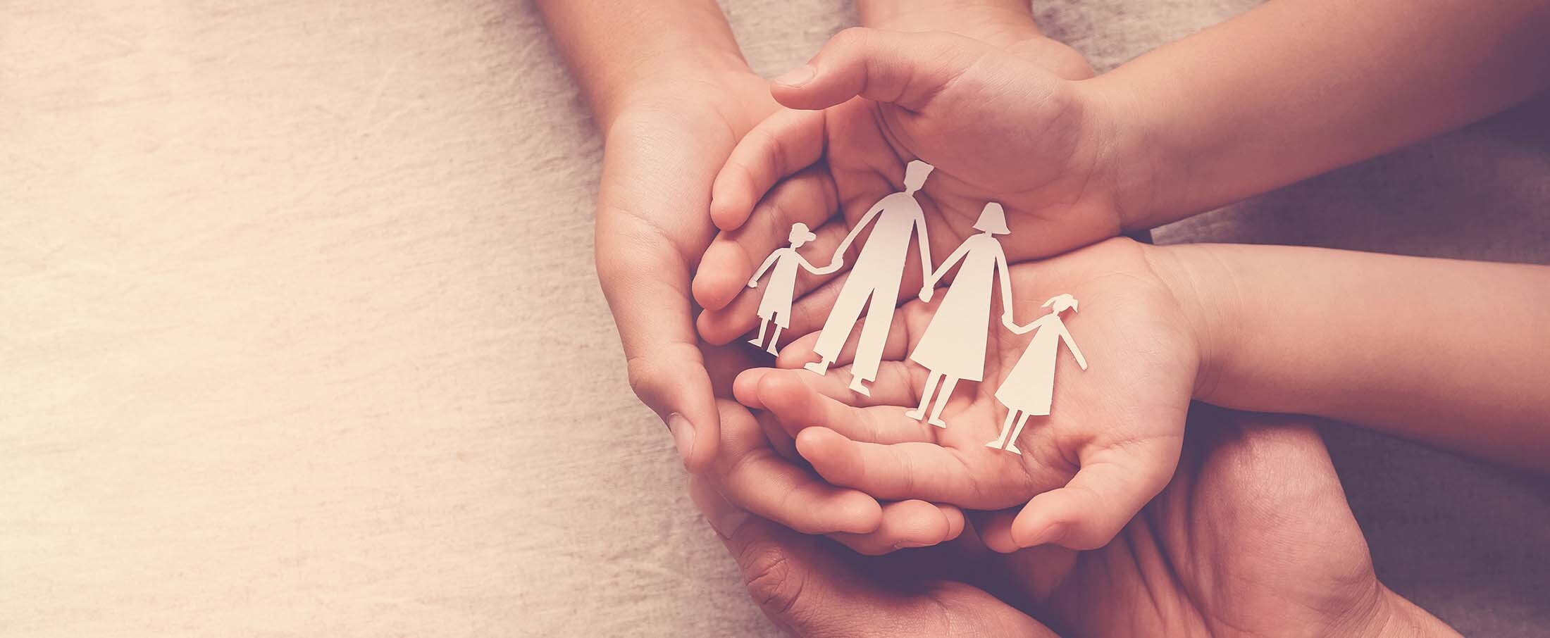 Hands holding a paper family.