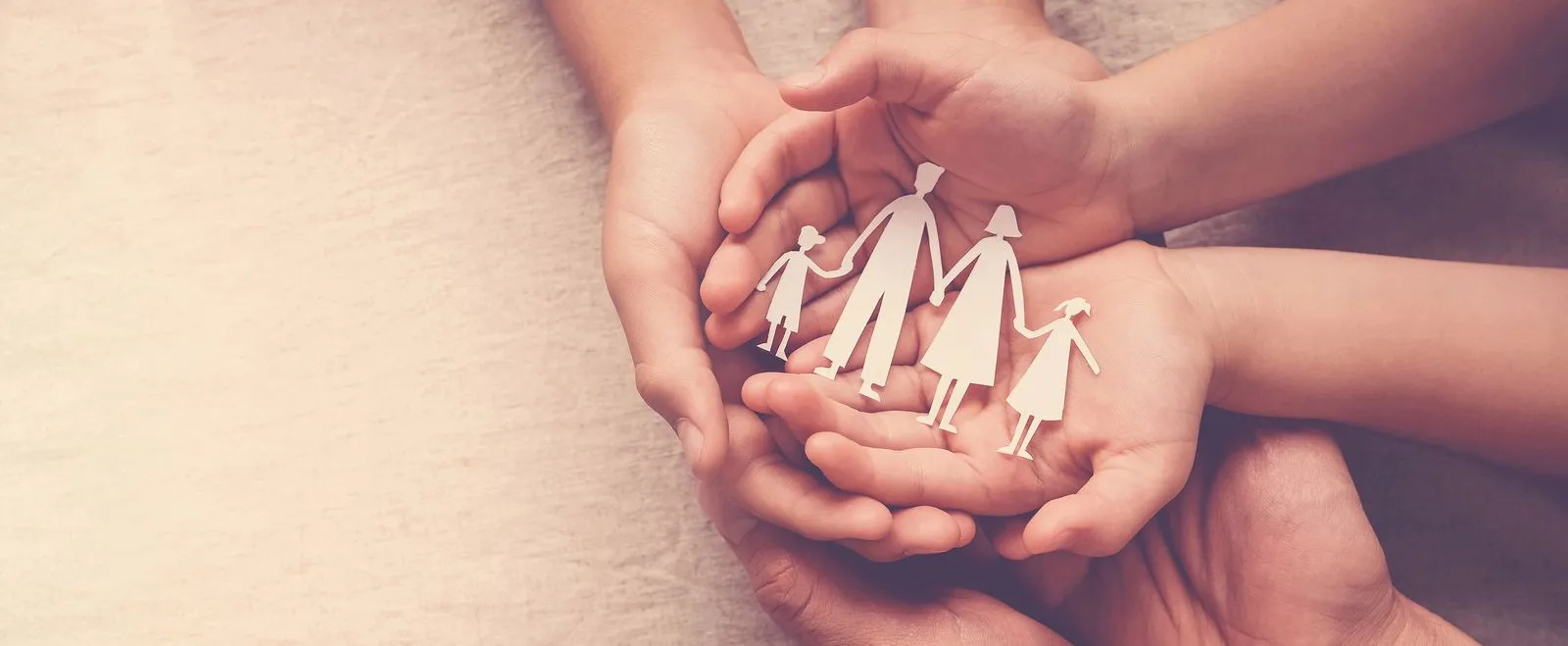 Hands holding a paper family.