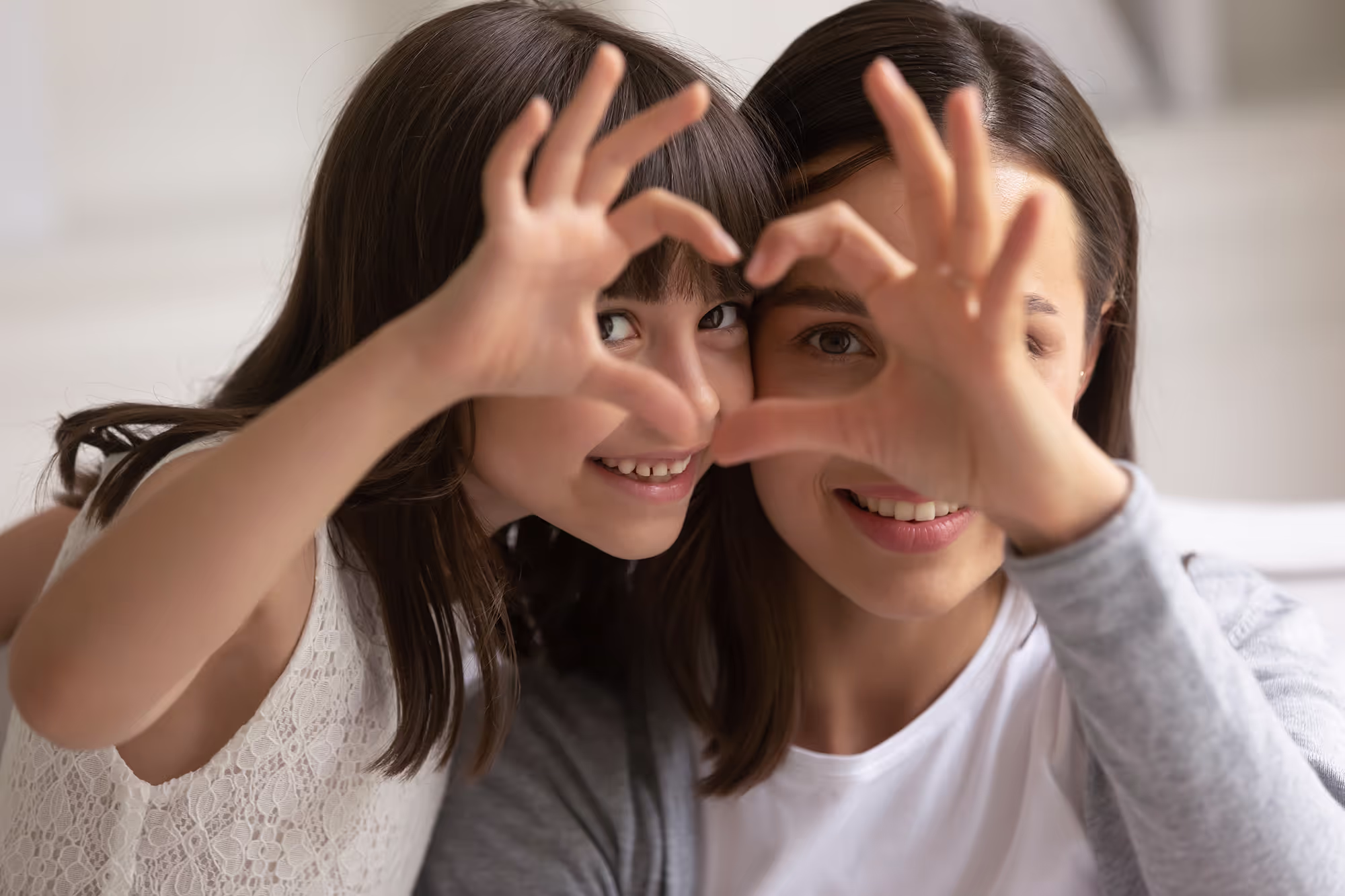 A mother and daughter making a heart with their hands.